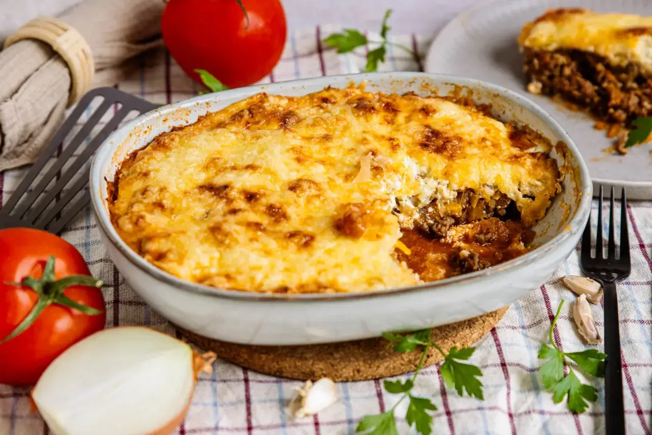 Herzhafter Krauttopf mit Hackfleisch im Backofen, goldbraun überbacken. Ein Stück ist bereits auf einem Teller angerichtet.