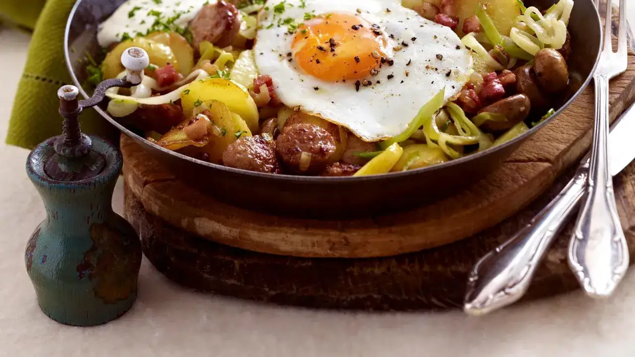 Herzhafte Bratkartoffeln mit Bratwurst, Speck und einem Spiegelei obendrauf. Ein deftiges Gericht, das Leib und Seele wärmt.