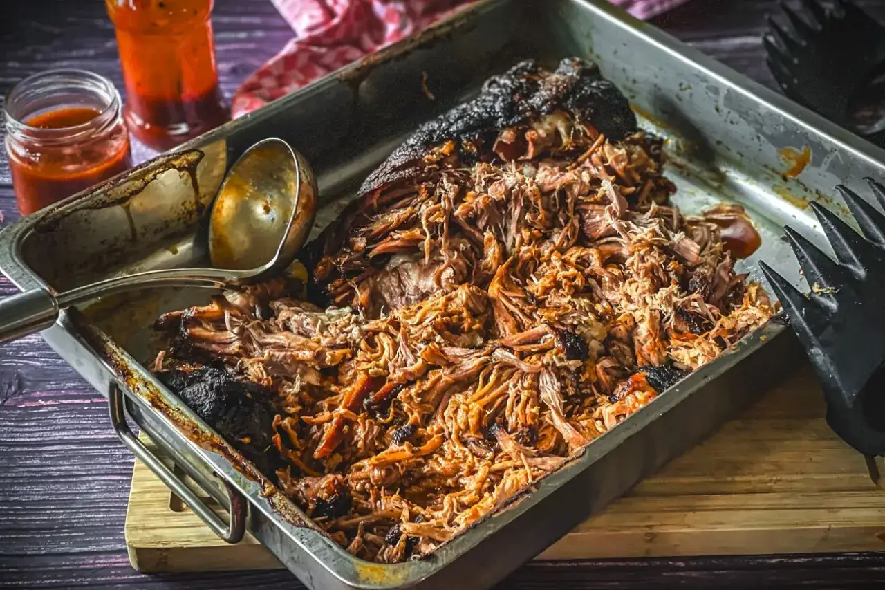 Pulled Pork im Bräter, perfekt für Gasgrill Rezepte. Saftiges Fleisch mit Sauce und Grillgabel.