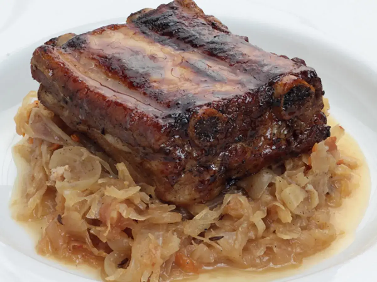 Herzhaftes Gericht: Rippchen mit Sauerkraut im Backofen, goldbraun gebraten und auf einem Bett aus gedünstetem Sauerkraut serviert.
