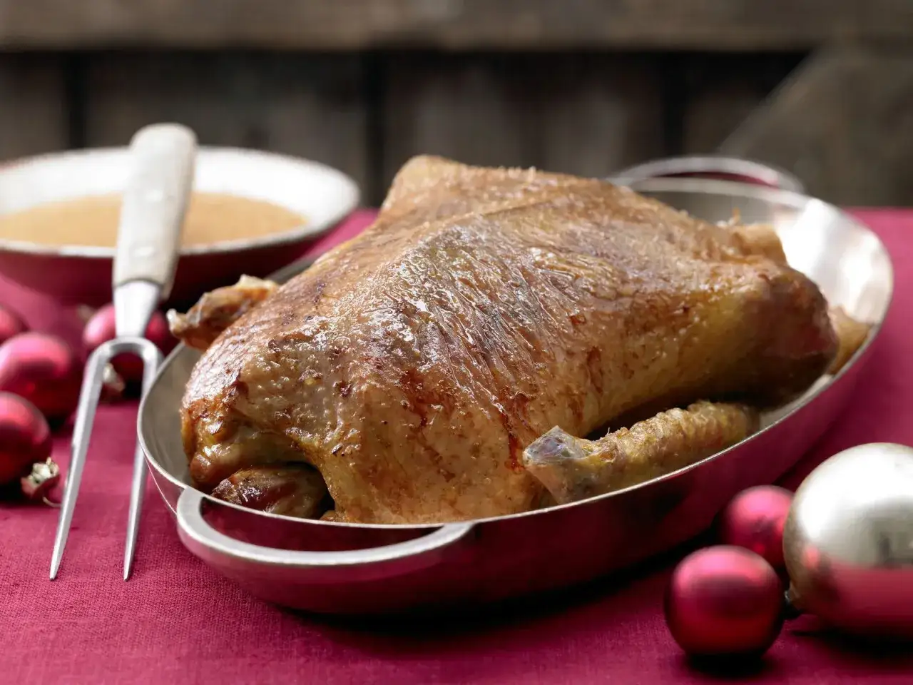 Eine halbe Ente braten, goldbraun und saftig, bereit zum Servieren mit Soße und weihnachtlichen Kugeln.