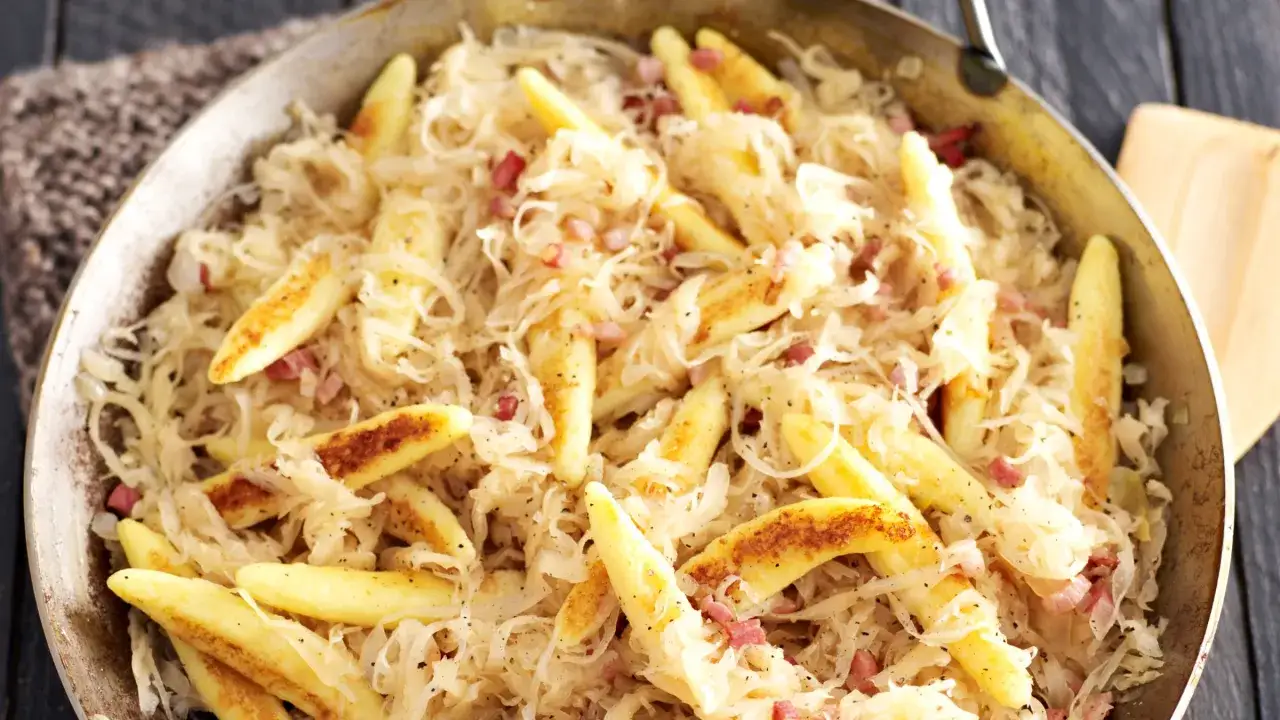 Herzhafte Schupfnudeln mit Sauerkraut und Speckwürfeln in einer Pfanne, ein deftiger Klassiker.