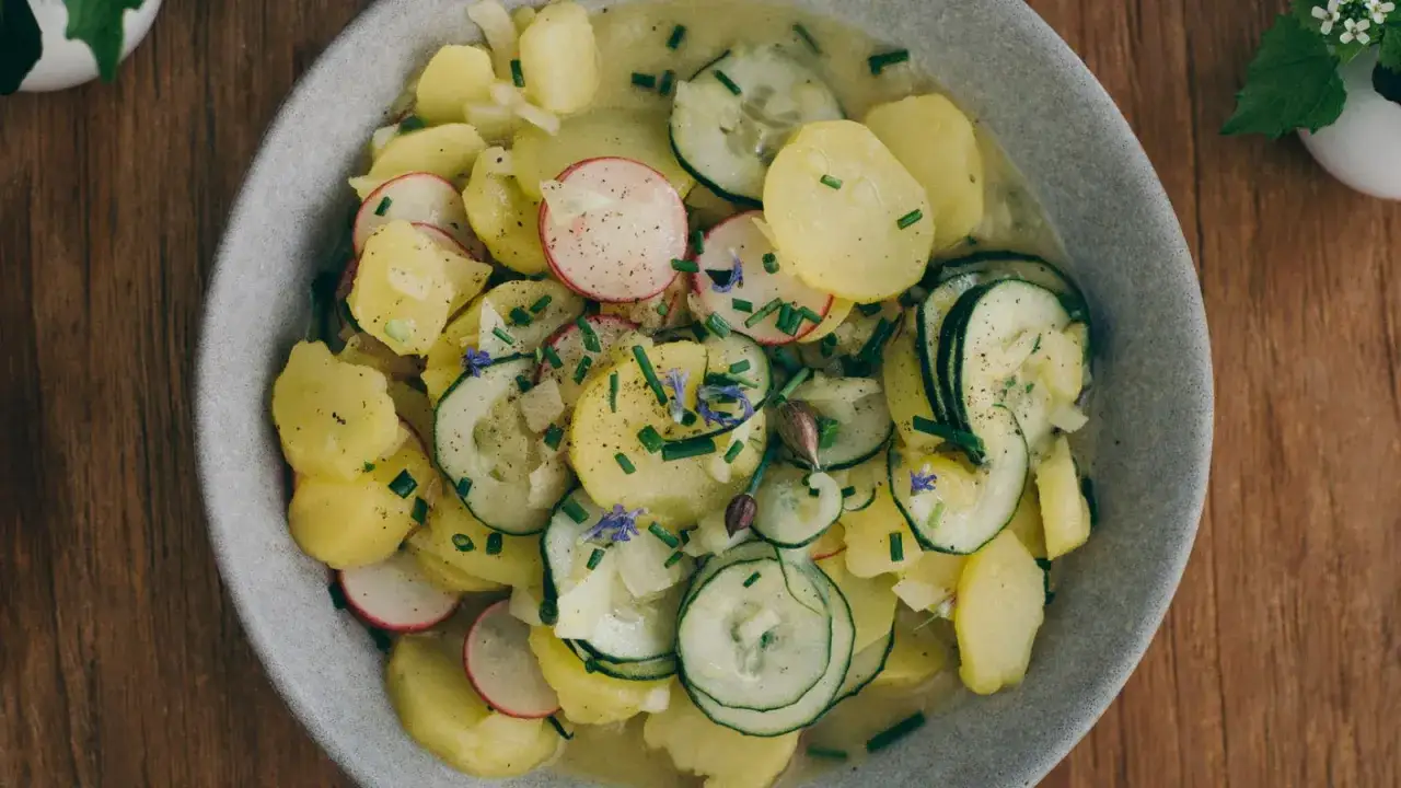 Ein frischer Kartoffelsalat ohne Mayo, mit Gurken, Radieschen und Schnittlauch garniert.