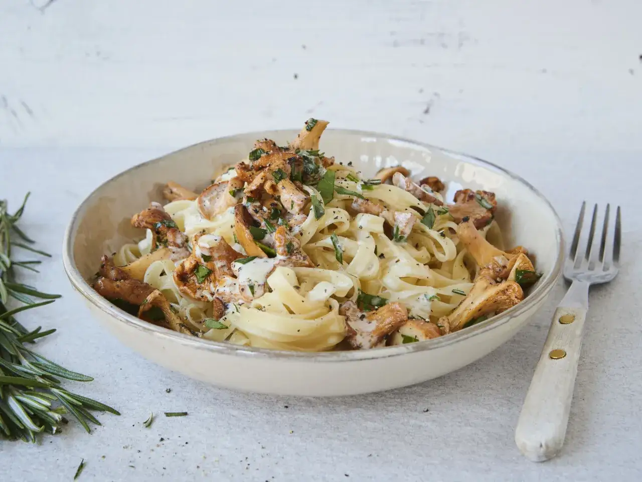 Cremige Tagliatelle mit gebratenen Pfifferlingen und frischer Petersilie, garniert mit schwarzem Pfeffer. Ein Genuss für alle Nudel- und Pilzliebhaber.