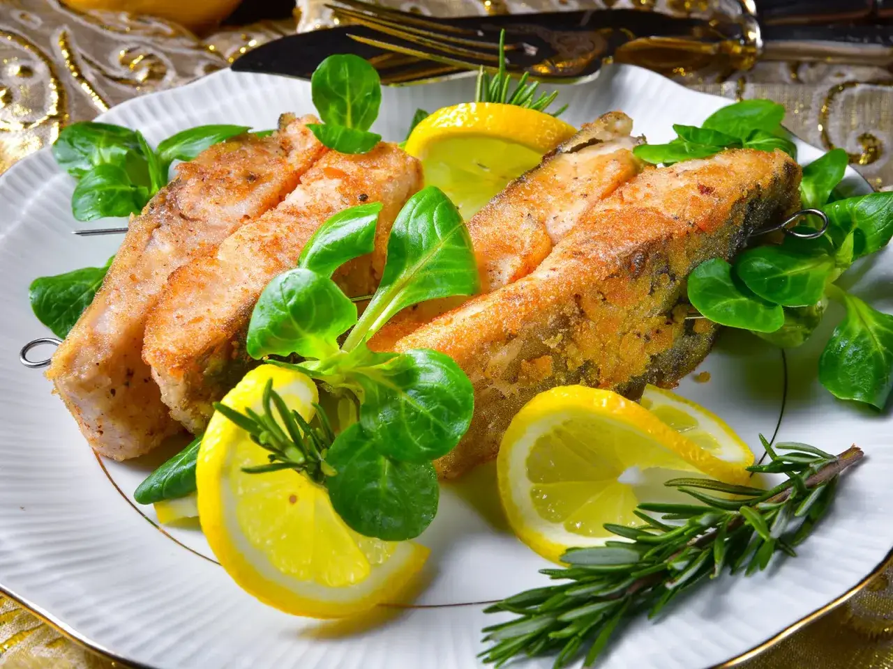 Gebratener Karpfenfilet mit Haut, garniert mit frischen Kräutern und Zitronenspalten.